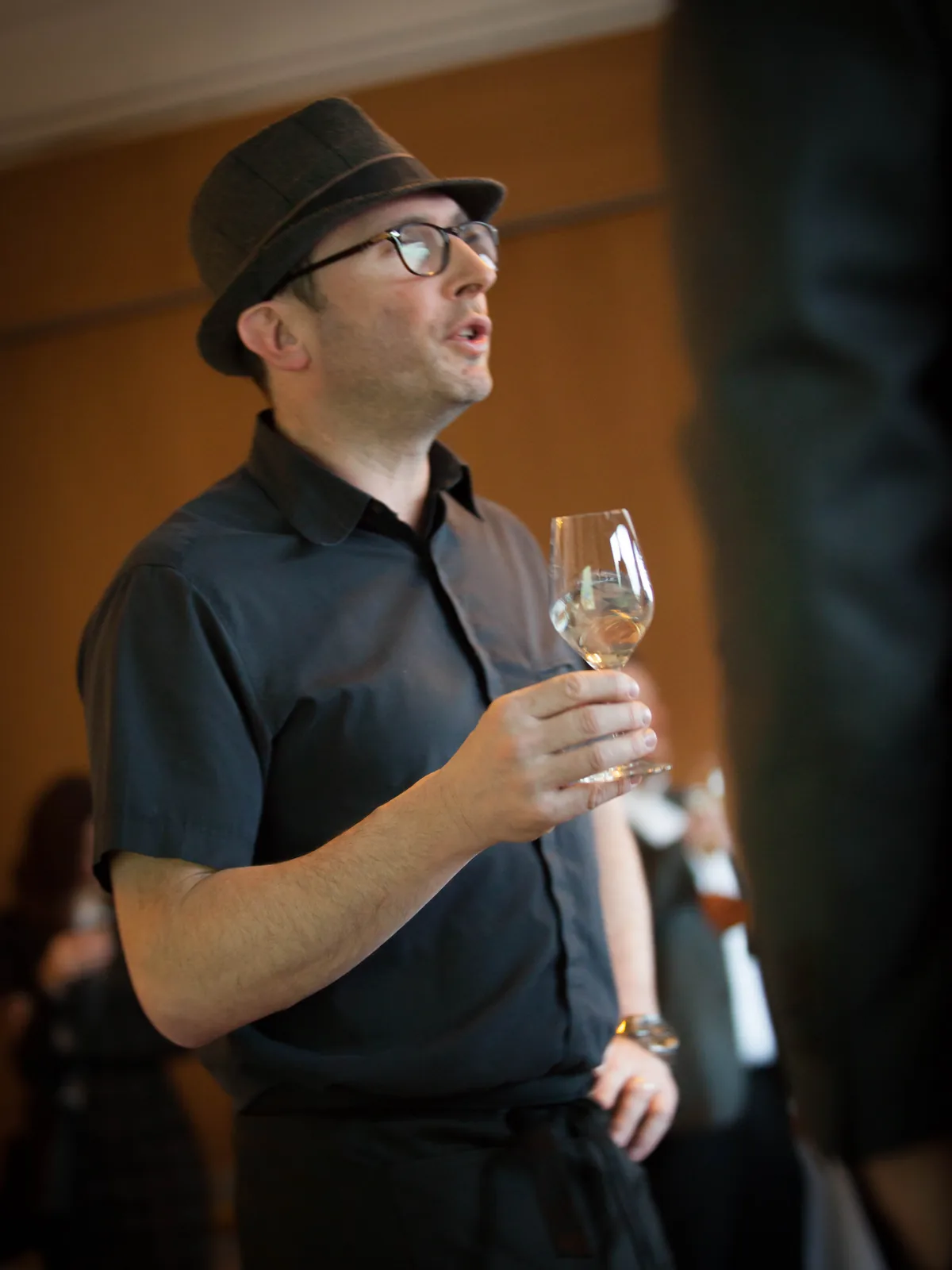 Romain Miller en atelier, verre à la main, commentant un vin devant un groupe.