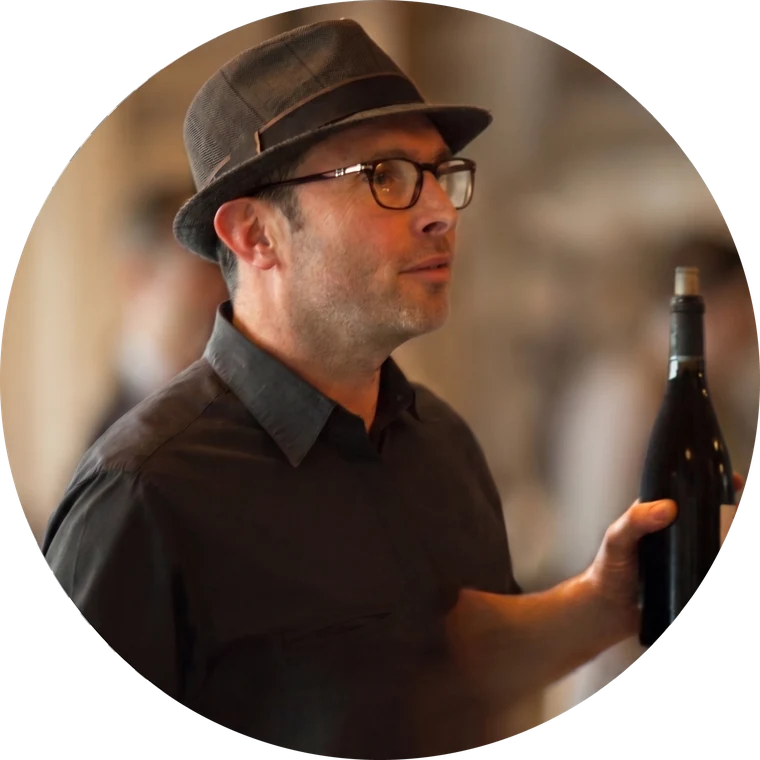 Romain Miller, chapeau et lunettes, présentant une bouteille lors d'un atelier.